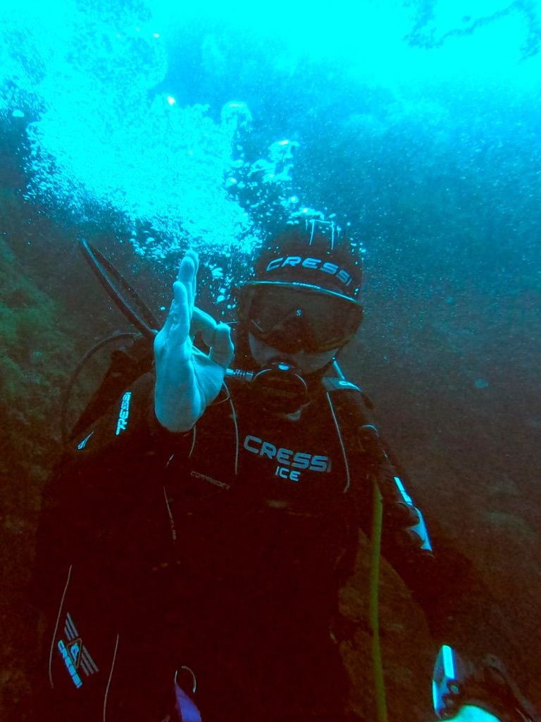 Plongeur faisant le signe OK sous l'eau, entouré de bulles